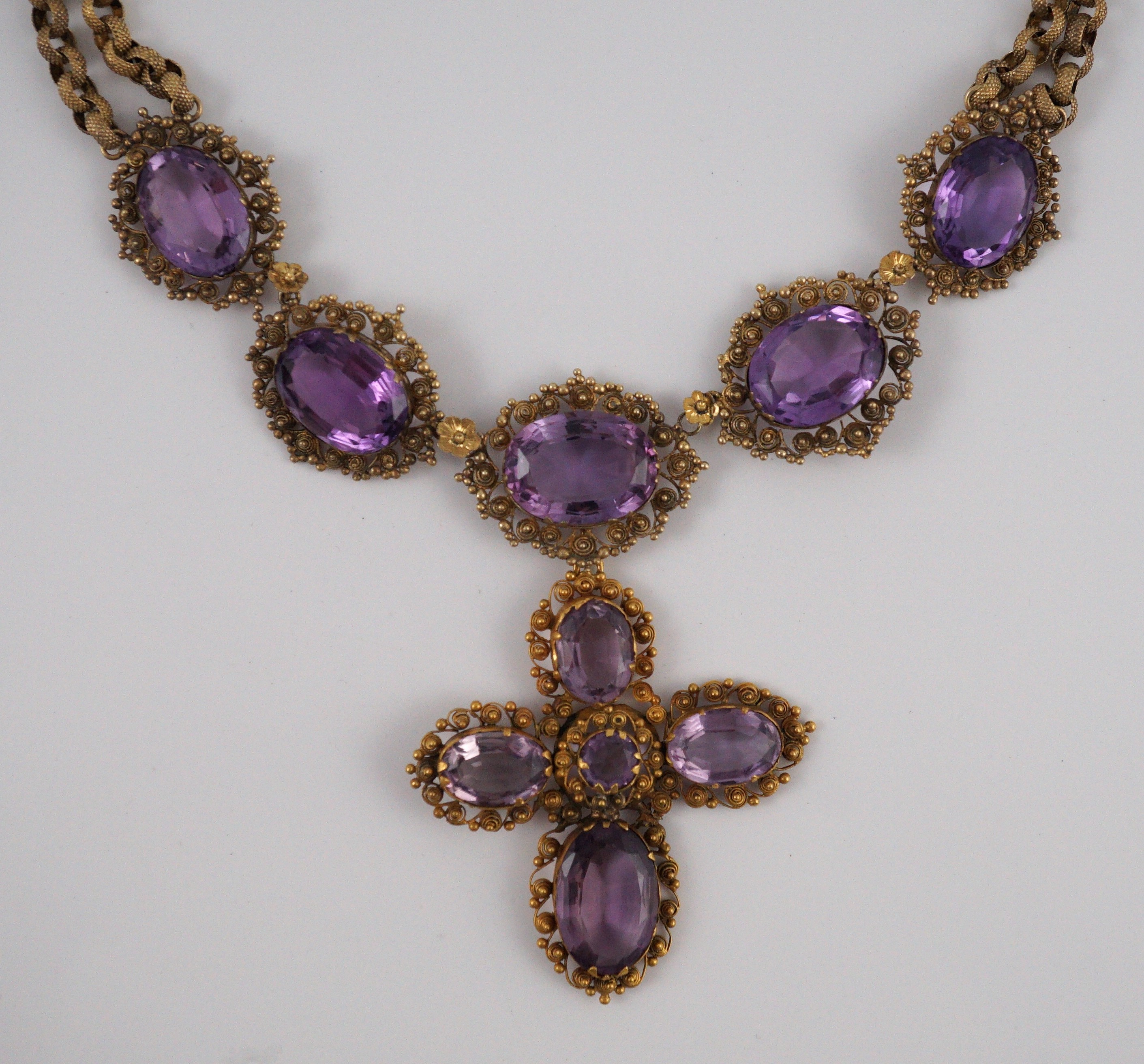 An early 19th century gold and eleven stone oval cut amethyst set pendant necklace and a similar cross pendant (repair)